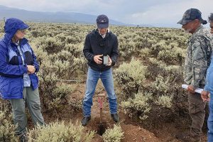 3 people digging a soil pit in a rangeland to take soil data